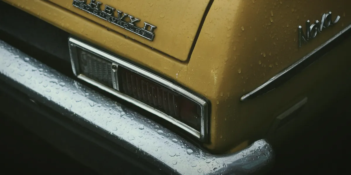 Rain on the chrome and badge of a classic collector car